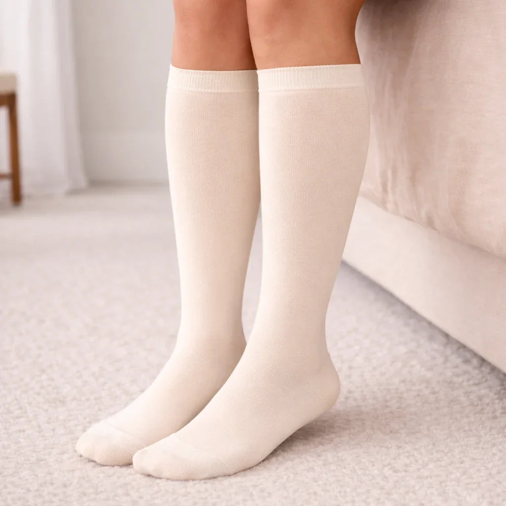 Woman wearing Glowbump maternity compression socks on beige carpeted bedroom floor